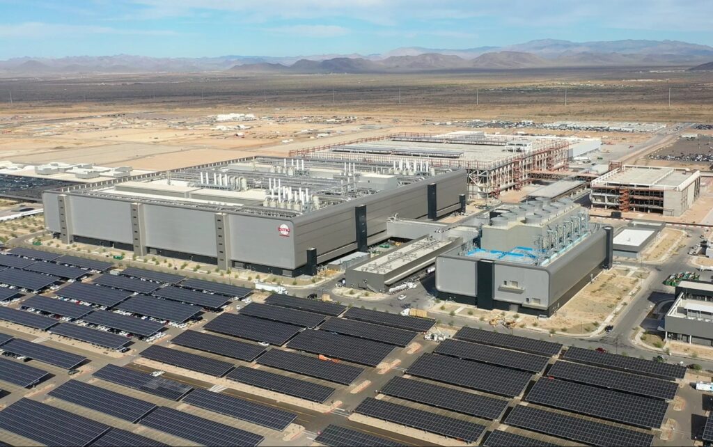 Aerial view of the TSMC semiconductor manufacturing facility in Phoenix, Arizona, showing the massive industrial complex surrounded by desert and solar panels.